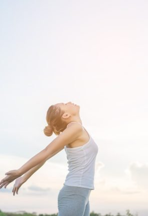 concentrated-woman-stretching-her-arms-with-sky-background.jpg